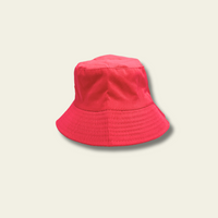 This reversible bucket hat is designed for children, offering protection from the sun with a functional and simple design. One side of the hat features a flamingo print in shades of blue and pink, while the reverse side is a pink solid color. Made from lightweight fabric, the hat is breathable and provides a comfortable fit for outdoor activities.