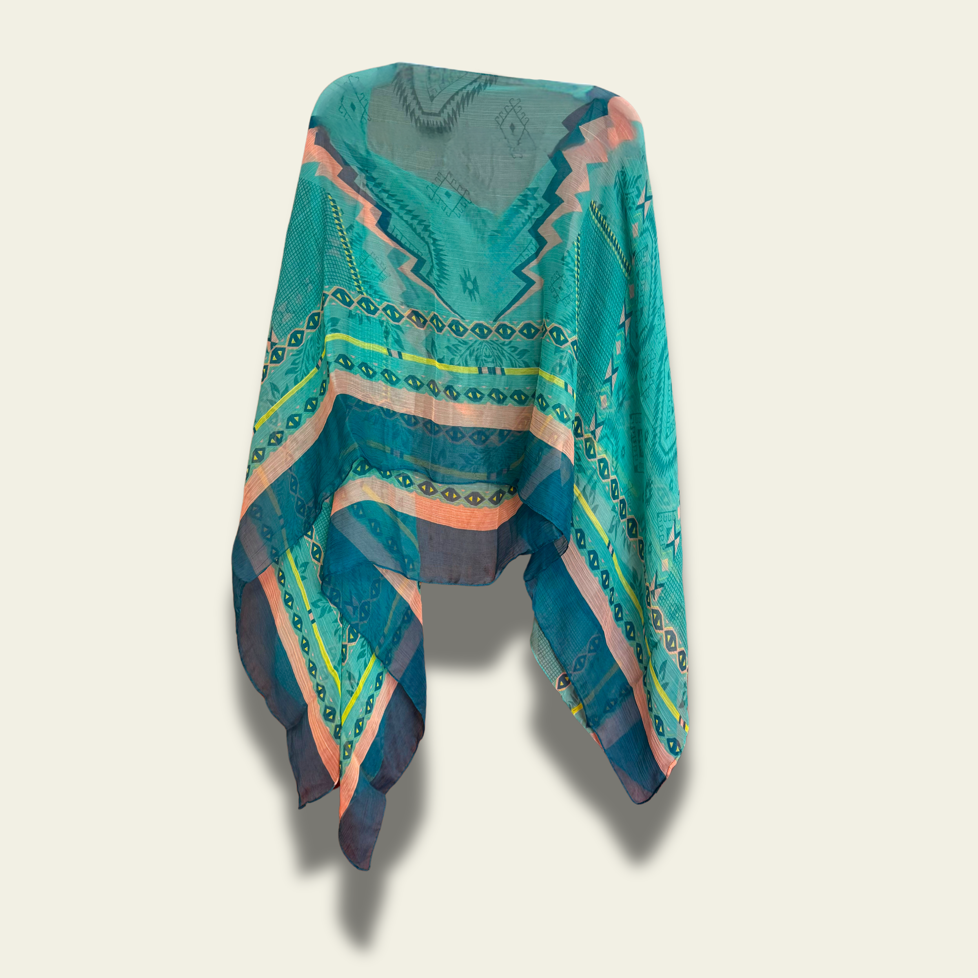 This lightweight chiffon poncho drapes beautifully, showcasing a vibrant blend of turquoise and coral with an abstract print. 