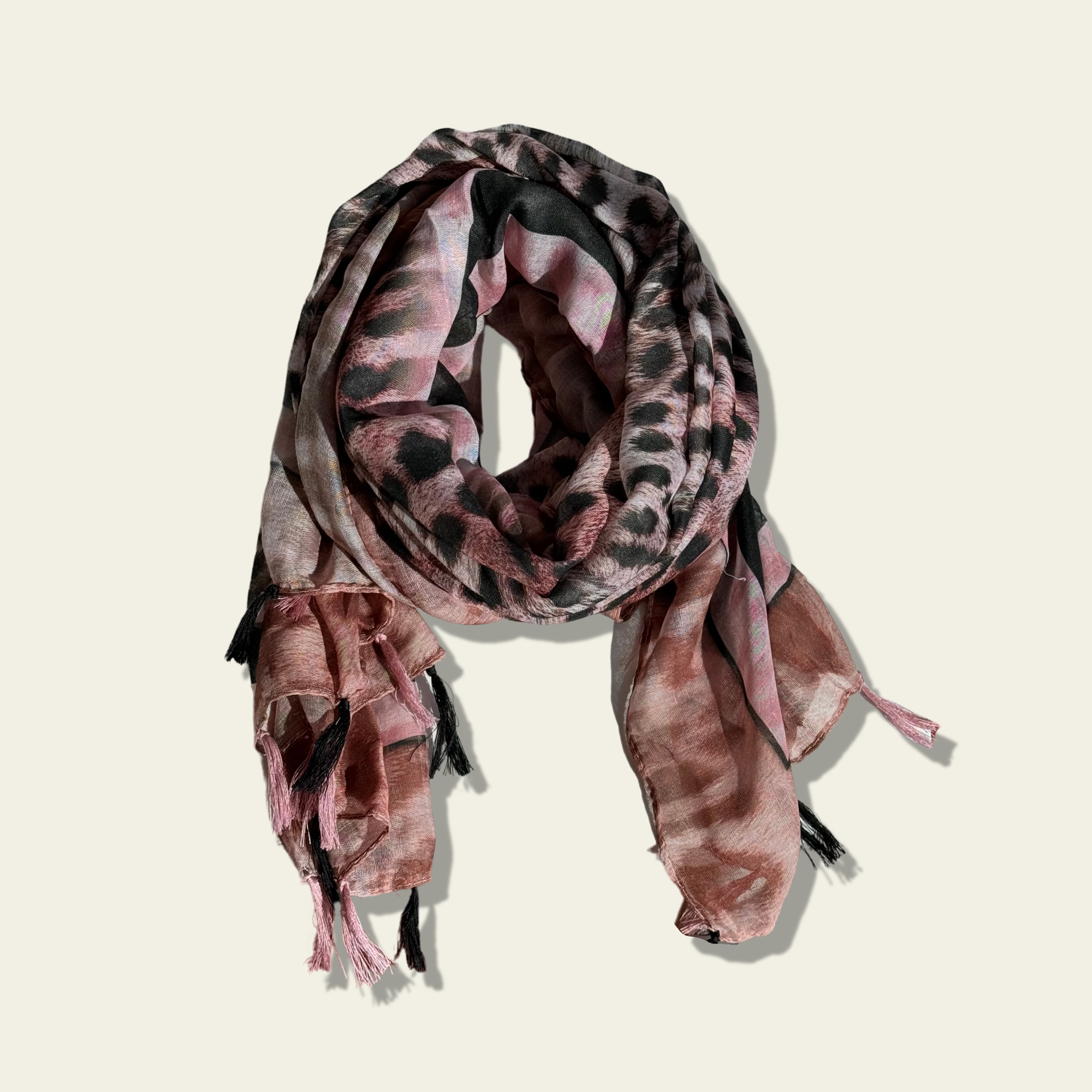 This pink animal print scarf is displayed neatly rolled up, ready to be styled and draped around the neck. Its soft, lightweight fabric provides comfort while adding a touch of bold pattern to any outfit. The versatile design allows it to be worn in a variety of ways, making it a perfect accessory for both casual and semi-formal occasions.