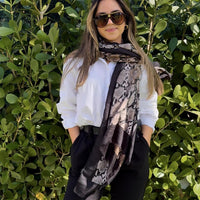 This animal print pashmina is elegantly draped over the shoulders of the model, showcasing its stylish design and soft, lightweight fabric. The pashmina features a bold animal print pattern, enhanced by a delicate black border that adds a sophisticated touch.