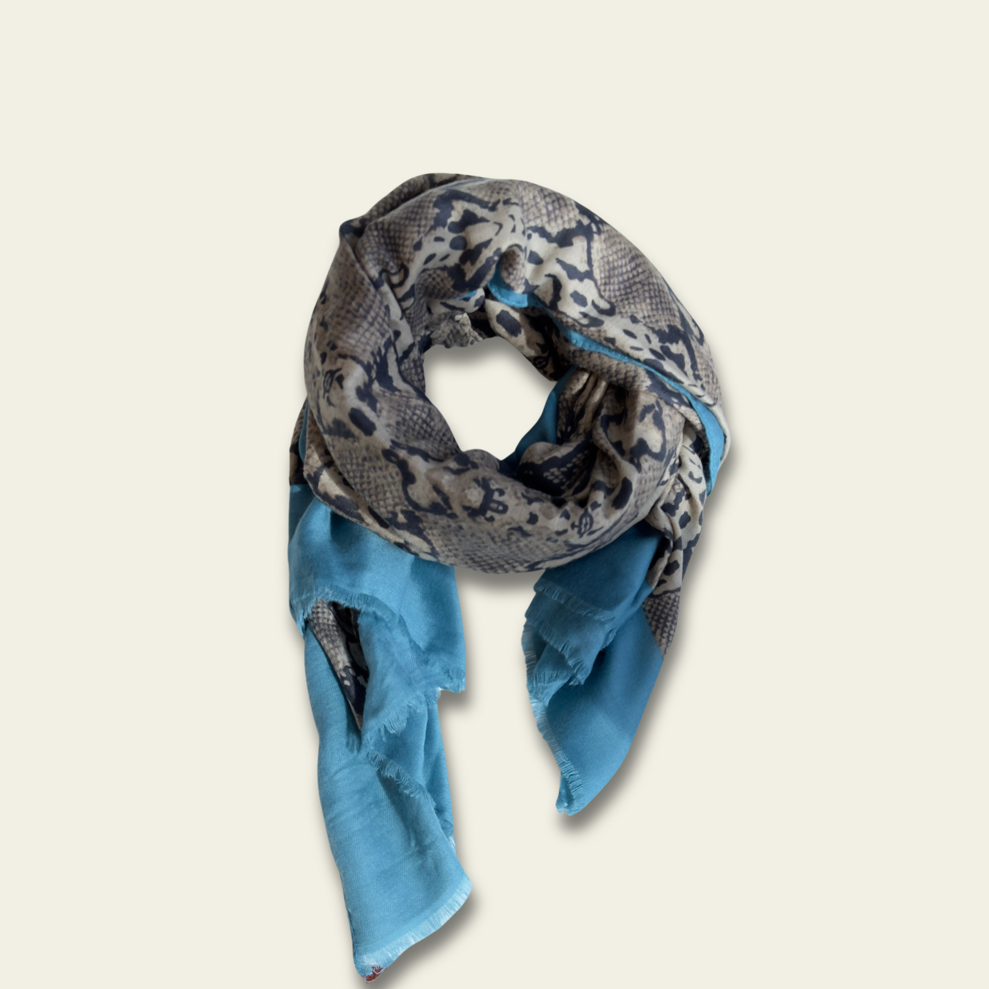 This animal print pashmina, featuring a bold pattern and a soft blue border, is displayed flat against a solid background to highlight its elegant design. The pashmina’s striking animal print is enhanced by the subtle blue edging, offering a modern and sophisticated touch. Made from soft, lightweight fabric, it provides both warmth and comfort, making it an ideal accessory for various occasions.