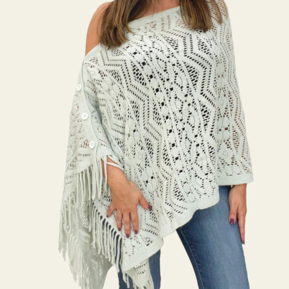 The knitted ivory Cardishawl is elegantly worn by the model, draped over one shoulder to reveal a relaxed, flattering fit. The soft, textured knit creates a cozy and breathable feel, while the loose, open design adds effortless charm and movement. The piece falls gracefully, offering a stylish, laid-back look that remains both comfortable and chic. Ideal for layering over casual or dressy outfits