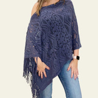 The knitted navy Cardishawl is elegantly worn by the model, draped over one shoulder to reveal a relaxed, flattering fit. The soft, textured knit creates a cozy and breathable feel, while the loose, open design adds effortless charm and movement. The piece falls gracefully, offering a stylish, laid-back look that remains both comfortable and chic. Ideal for layering over casual or dressy outfits