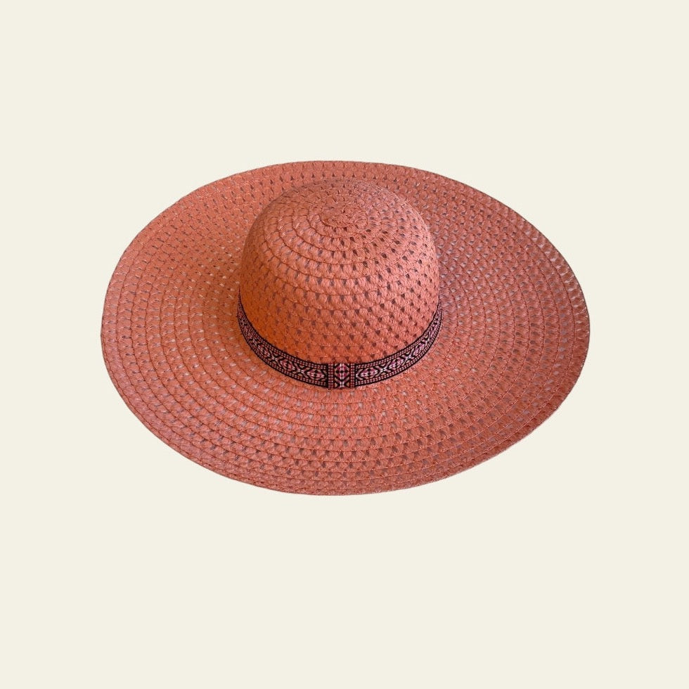 The hat is complemented by a sleek black band adorned with an abstract print adding a unique, artistic touch. The combination of the bold orange with the contrasting black band creates a striking design that stands out while maintaining a stylish, modern aesthetic. Lightweight and comfortable, this hat offers sun protection and adds a pop of color to any outfit.