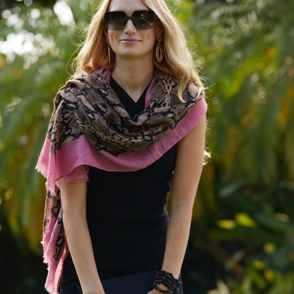 This animal print pashmina is elegantly draped over the shoulders of the model, showcasing its stylish design and soft, lightweight fabric. The pashmina features a bold animal print pattern, enhanced by a delicate pink border that adds a sophisticated touch.