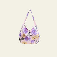 This Boho Bag features a striking floral print with vibrant, colorful flowers that beautifully contrast against the light pink background of the fabric. Crafted from a silky material, the bag offers a smooth, luxurious feel while maintaining durability and flexibility. Its foldable design adds a practical element, allowing for easy storage and portability. 