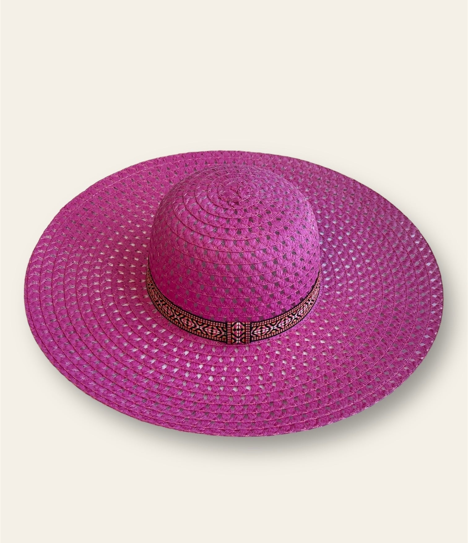 The hat is complemented by a sleek black band adorned with an abstract print adding a unique, artistic touch. The combination of the bold pink with the contrasting black band creates a striking design that stands out while maintaining a stylish, modern aesthetic. Lightweight and comfortable, this hat offers sun protection and adds a pop of color to any outfit.